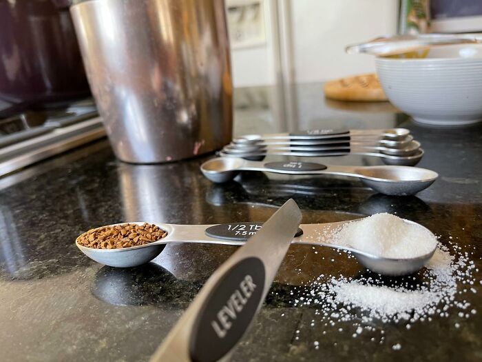 Measuring spoons on a kitchen counter with coffee granules and sugar, perfect for simplifying meal prep.
