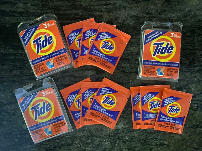 Travel-sized Tide detergent packs on a dark surface, ideal for budget-friendly vacations.