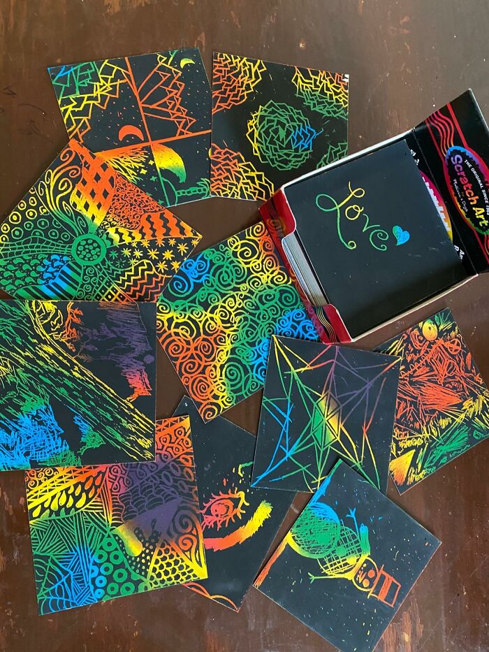 Colorful scratch art sheets with vibrant, glitter-like patterns spread on a table.