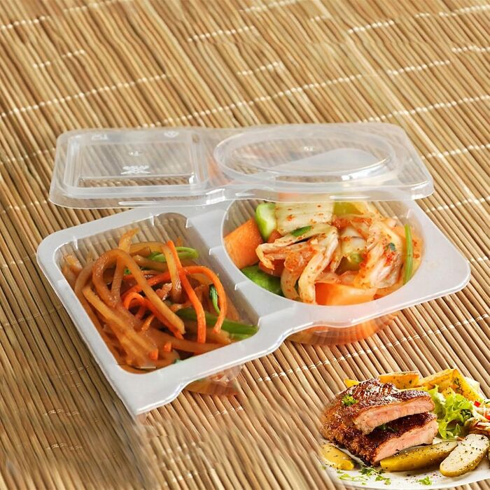 Meal prep container with vegetables on a bamboo mat.