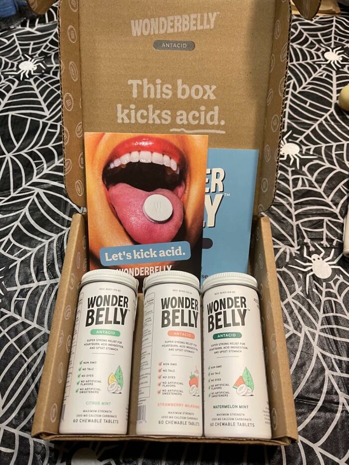 Wonderbelly antacid products in a box with "Let's kick acid" slogan on a vibrant booklet.