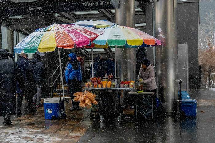 Street food vendor in snowy weather, showcasing colorful umbrellas at the 2025 World Food Photography Awards.