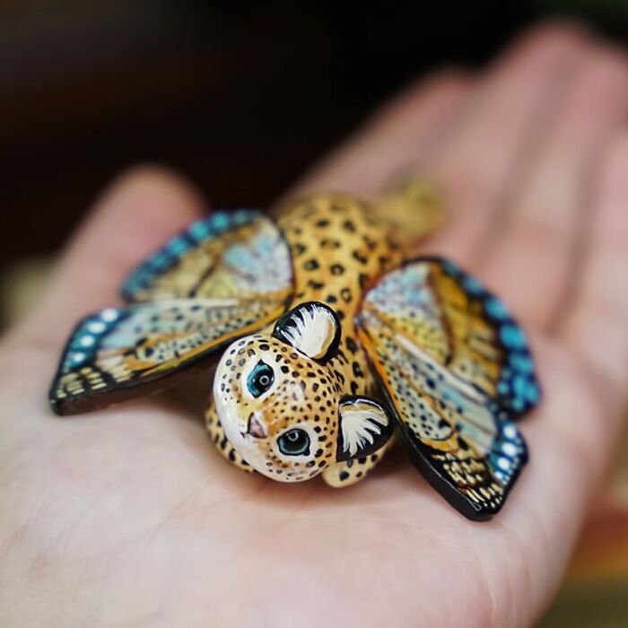 Pocket-sized animal figurine by Vallavica, featuring a whimsical leopard with butterfly wings, resting on an open palm.
