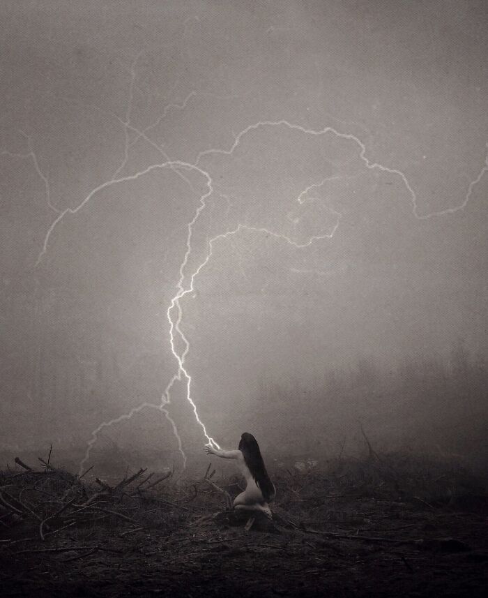 Dark escapism photography of a figure reaching towards lightning in a misty landscape.