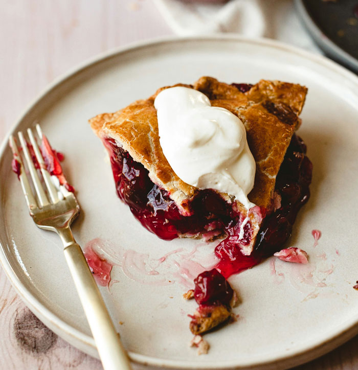 Slice of cherry pie with whipped cream on a plate, illustrating unconventional job hunting context.
