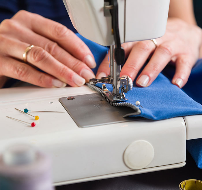 Hands sewing blue fabric on a machine, symbolizing Chinese artistry amidst U.S. tariff tensions. Hands sewing blue fabric on a machine, symbolizing Chinese artistry amidst U.S. tariff tensions.