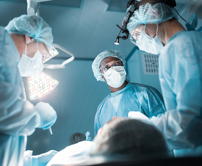 Surgeons in an operating room performing a medical procedure in a clinical setting.