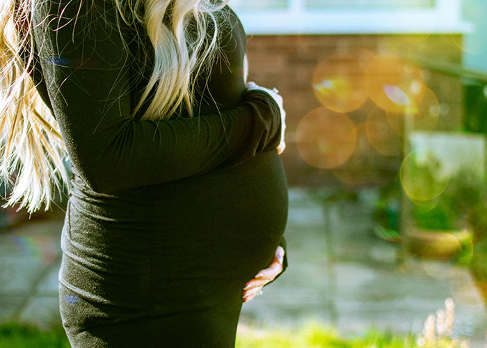 Pregnant woman in black dress outdoors, illustrating heartbroken people realizing their significant others were cheating.
