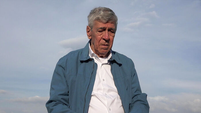 Elderly man outdoors in a blue jacket, illustrating realities of aging.