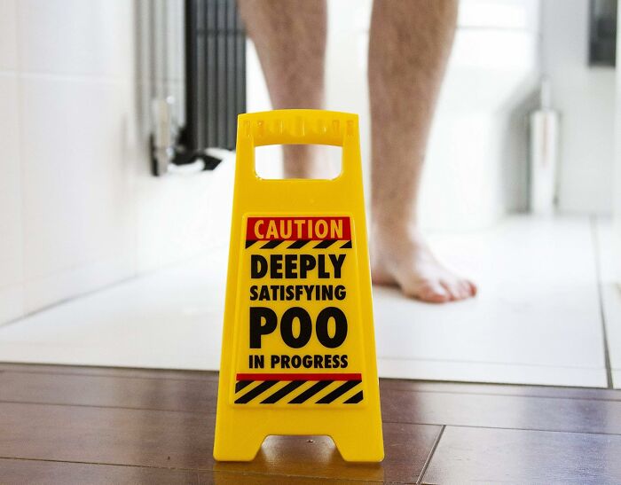 Yellow caution sign with humorous text in bathroom setting, highlighting ridiculous finds.