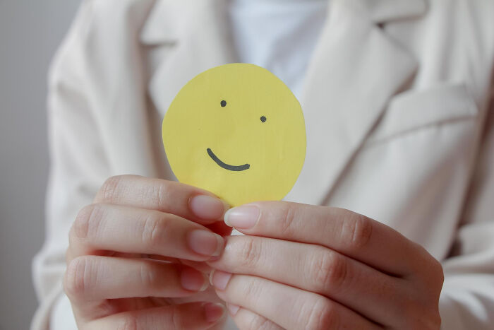 Person holding a yellow smiley face cutout, symbolizing different perspectives in dating.