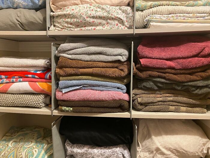 Folded towels and linens neatly organized in cubbies, showcasing genius organization finds for home storage under 20 dollars.