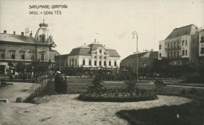 Black and white photo of a European town square, showing architecture and street life from 100 years ago.