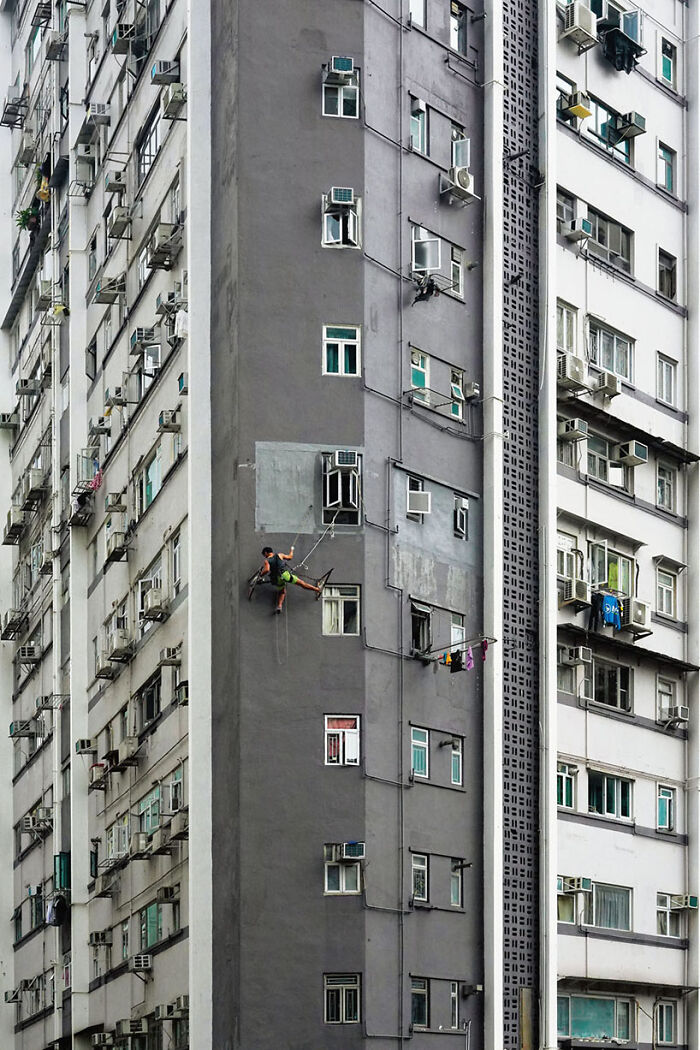 Abseil Drilling, 2023 - A Man Is Drilling A Hole On The Facade Of A Building In Order To Fix The Metallic Support For The Bamboo Scaffolding