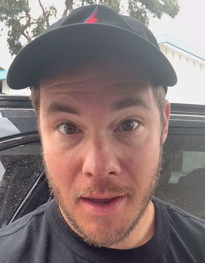 Actor involved in cement truck crash, wearing a black cap, outside near a vehicle.