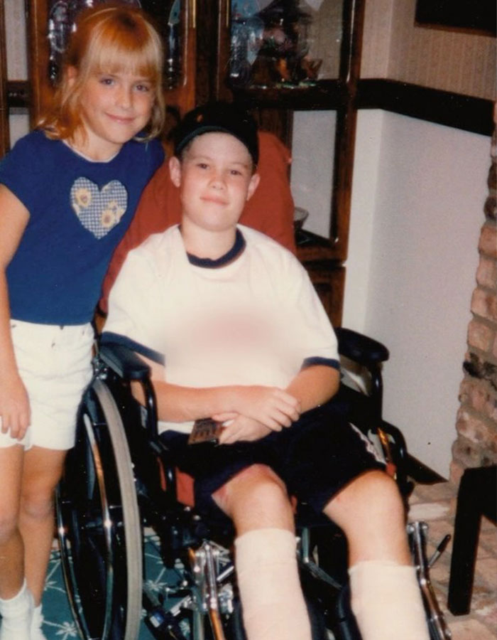 Two children, one in a wheelchair with leg casts, inside a home setting, highlighting 'Pitch Perfect' actor's accident impact.