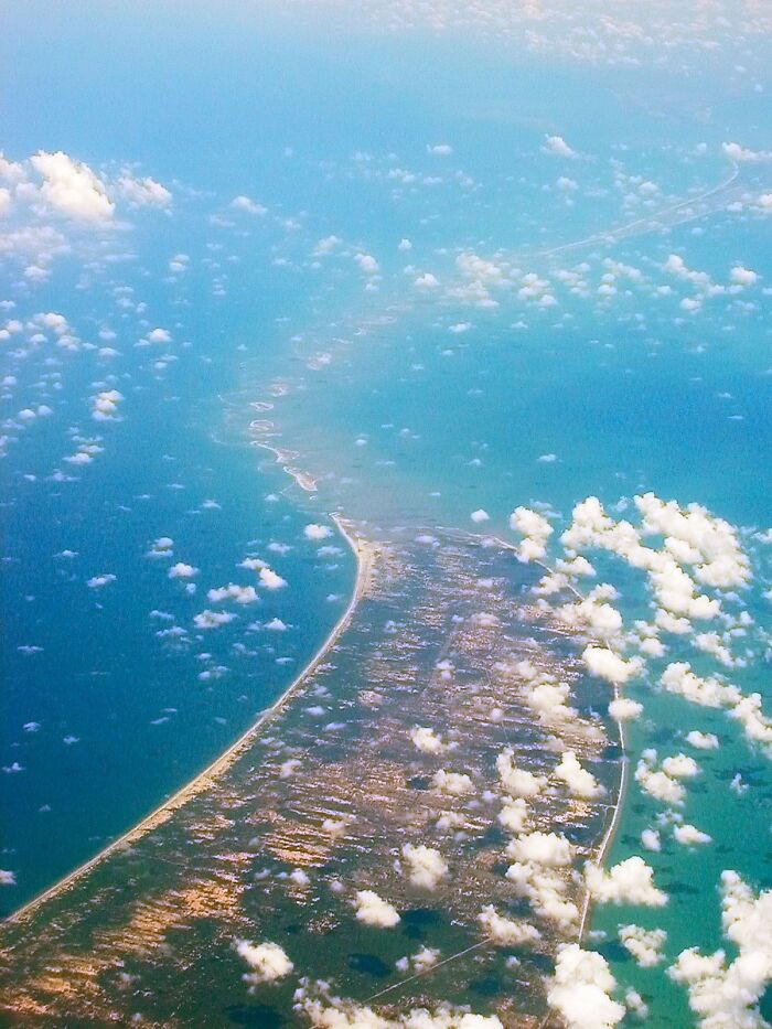 Aerial view of an ancient artifact site stretching across the sea, shrouded in clouds.