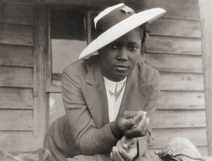 African American woman in a vintage suit and hat, showcasing strength and resilience over a century ago in black and white photo.