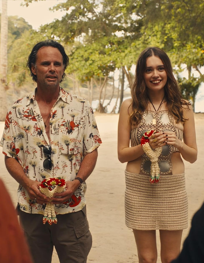 Two people holding flowers, outdoors on a beach, related to White Lotus.