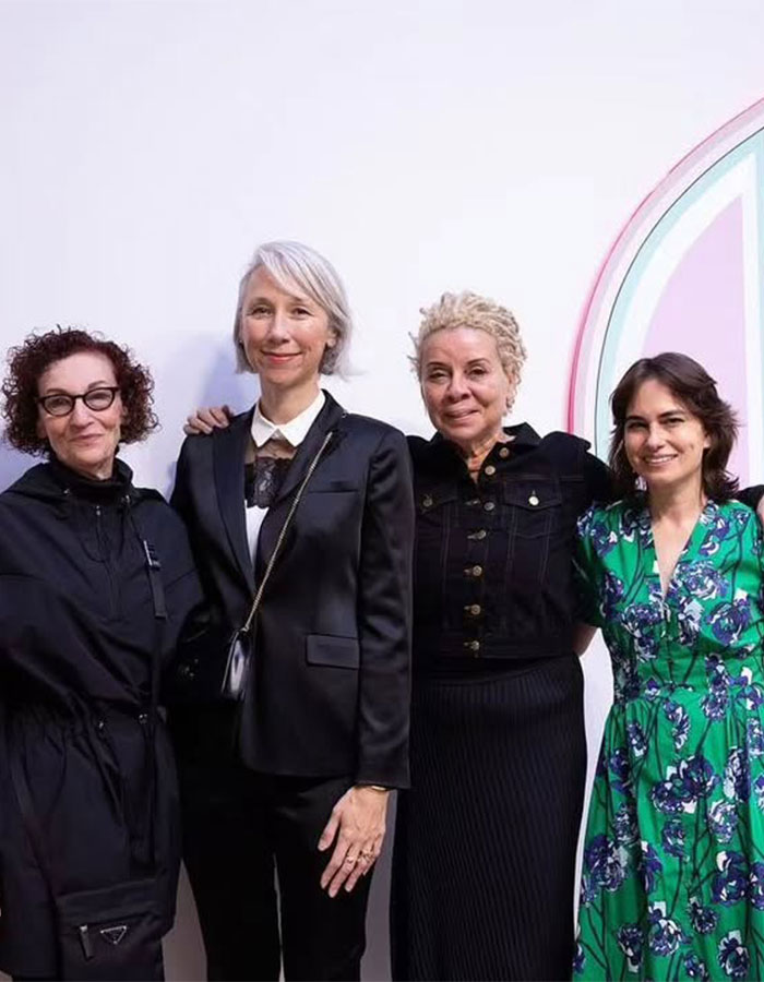 Four women standing together posing for a photo at an event, each with distinct fashion styles. 