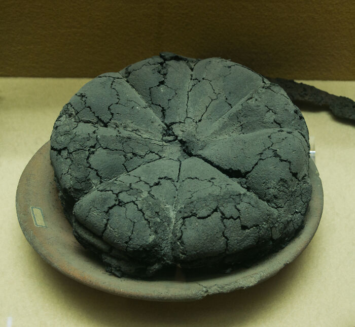 Ancient charcoal-burned bread artifact displayed on a clay platter, illustrating a fascinating history lesson.