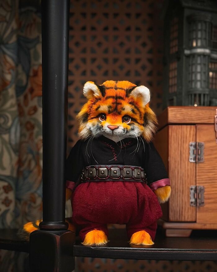 Whimsical plush toy resembling a tiger in detailed costume, displayed on a shelf.