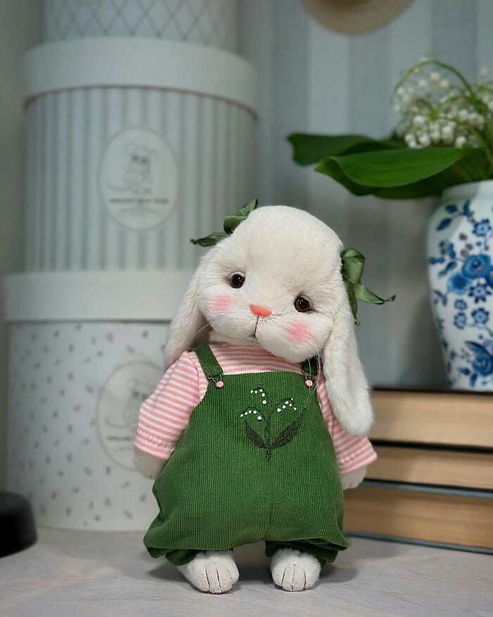 Whimsical plush toy of a cute rabbit dressed in green overalls with floral embroidery, showcasing handmade artistry.