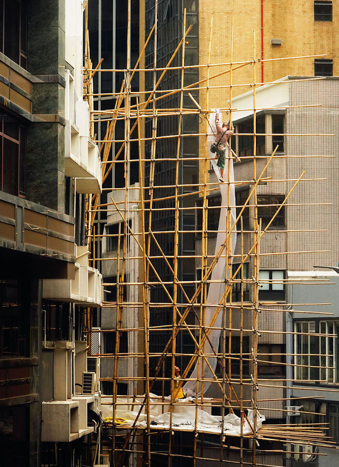 Ascending Bamboos, 2023 - A Scaffolder Is Bringing Up The Fabric That Will Wrap The Bamboo Scaffolding He Did