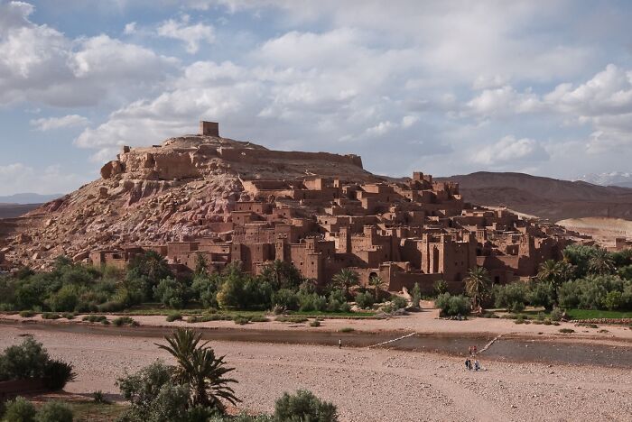 Ancient fortress on a desert hill under a blue sky, exemplifying lesser-known architectural wonders.