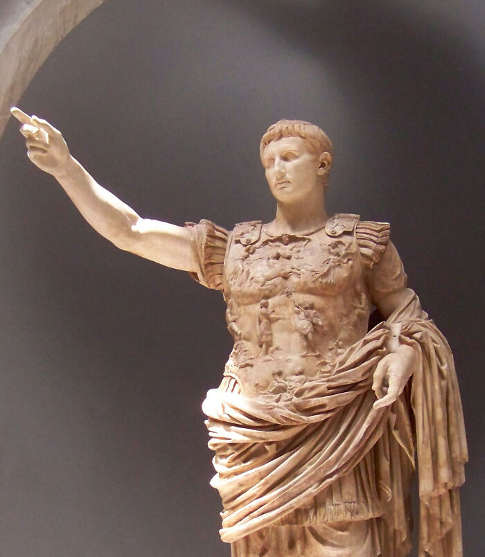 Statue of a Roman emperor in traditional armor with an outstretched arm, representing Roman Empire art.