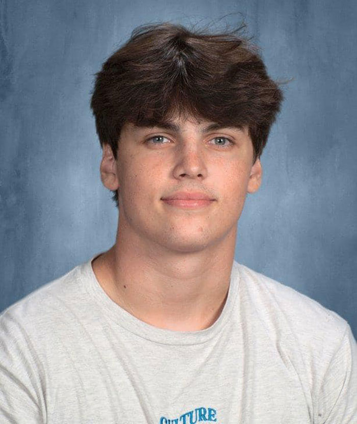 Young teen in a white shirt against a blue background, related to a heartbreaking final post and tragedy with twin brother.