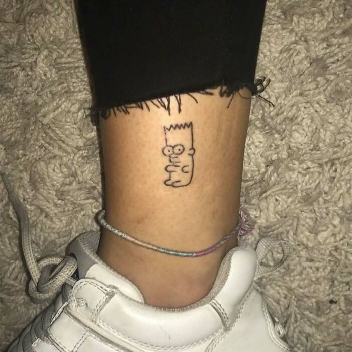 Simple Simpsons tattoo featuring Bart on a person's ankle above a white sneaker.