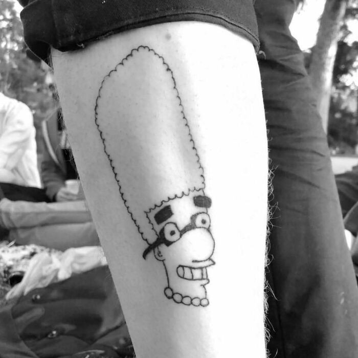 Simpsons tattoo featuring a quirky Marge design on someone's leg in a park setting.