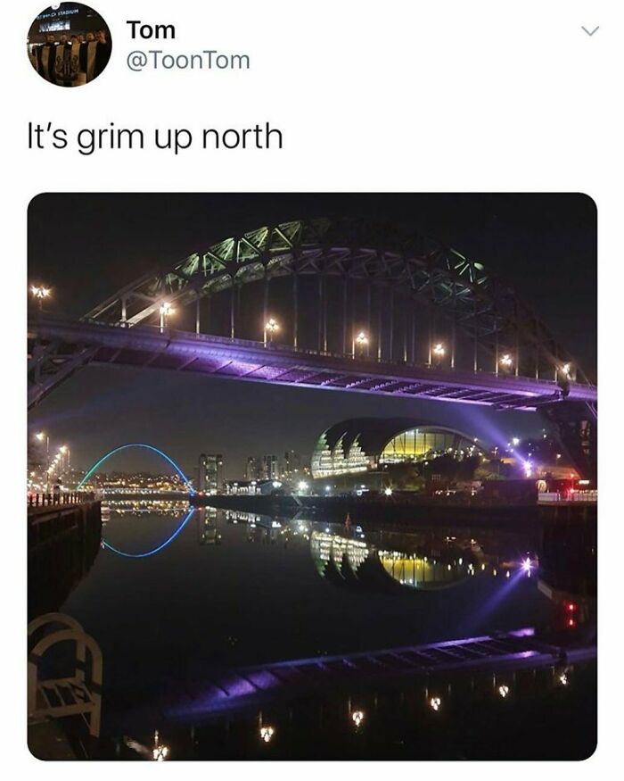 Night view of illuminated bridge in a British cityscape, humorously captioned "It's grim up north."