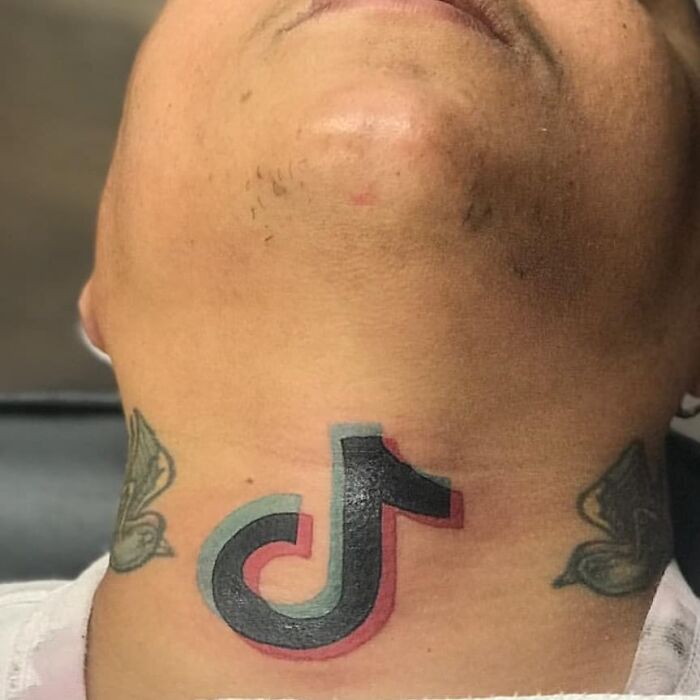 Neck tattoo of the TikTok logo with additional designs on each side, representing permanent mistakes.