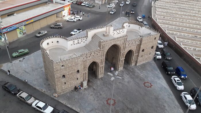 Aerial view of a lesser-known architectural wonder, featuring a historic stone gateway surrounded by cars and city streets.