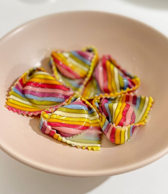 Colorful, handcrafted pasta with vibrant patterns in a beige bowl.