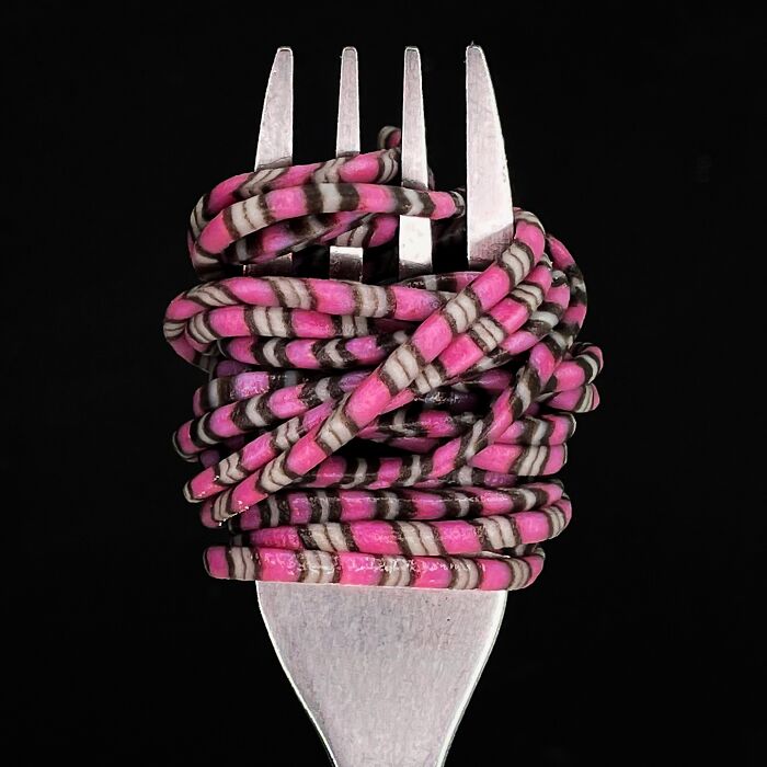 Colorful handcrafted pasta with pink and gray stripes, artistically wrapped on a fork.