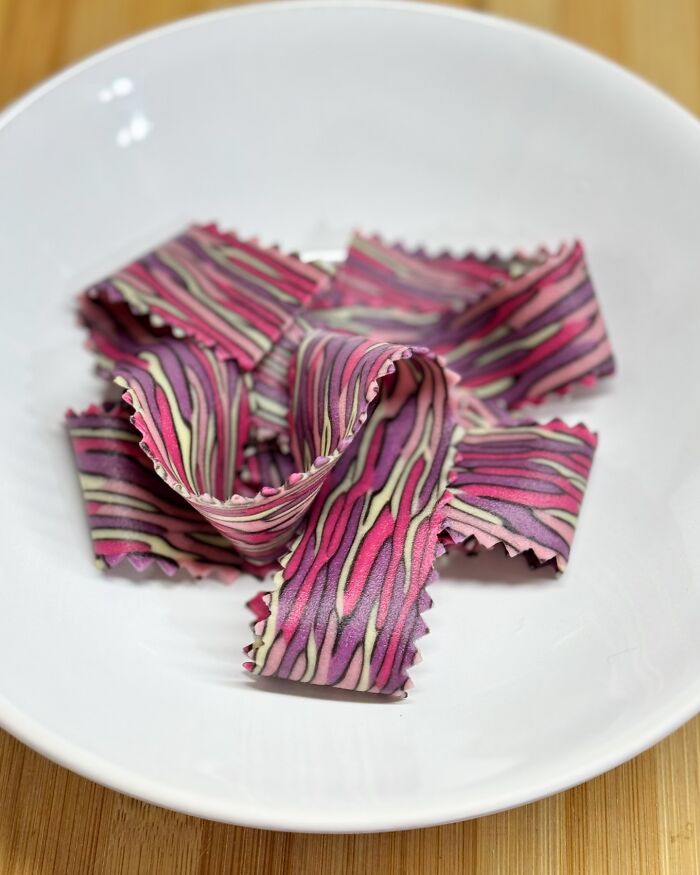 Colorful handcrafted pasta with intricate patterns on a white plate, showcasing culinary artistry.