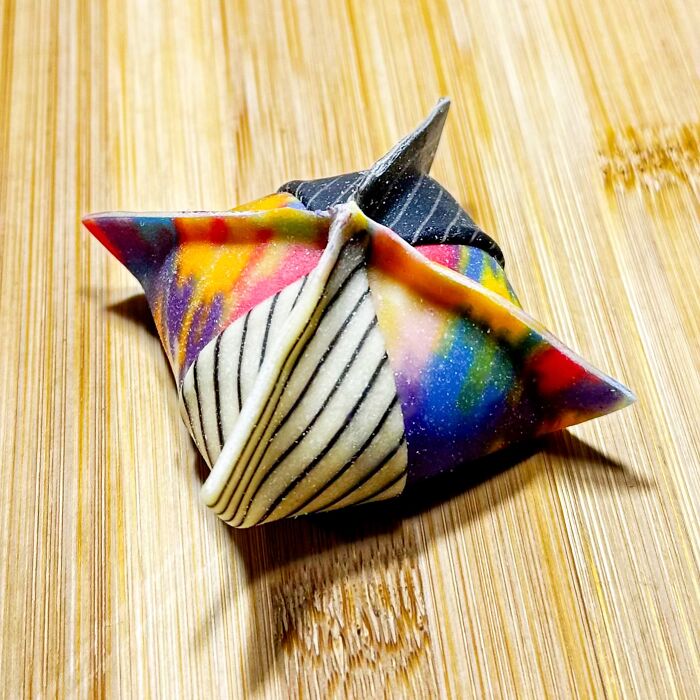 Colorful handcrafted pasta with vibrant patterns, crafted by a culinary artist on a wooden surface.