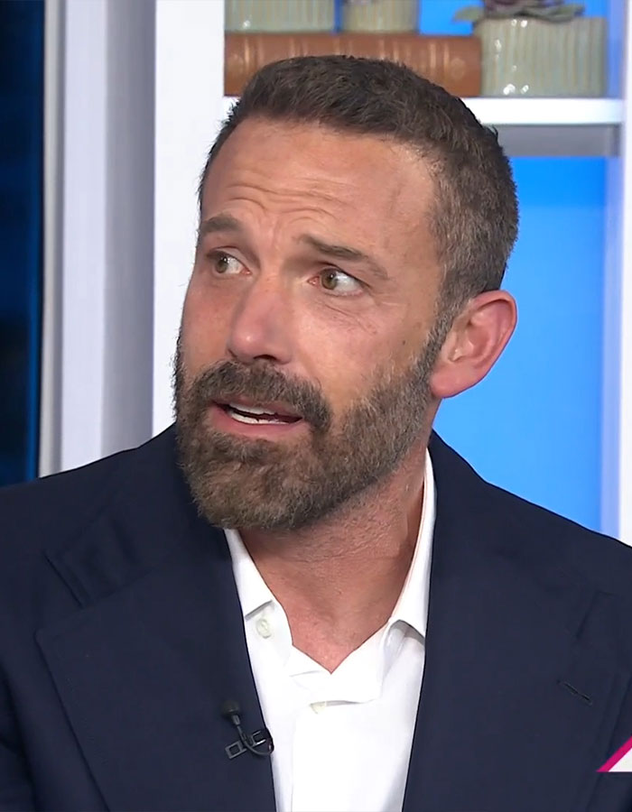 Man speaking in an interview, wearing a suit, discussing his approach to parenting and children's work ethic.