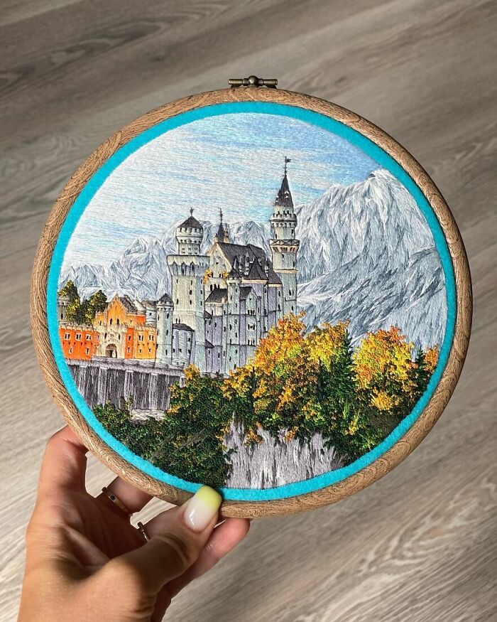 Intricate embroidery work depicting a castle and mountains, showcasing impressive detail and vibrant colors.