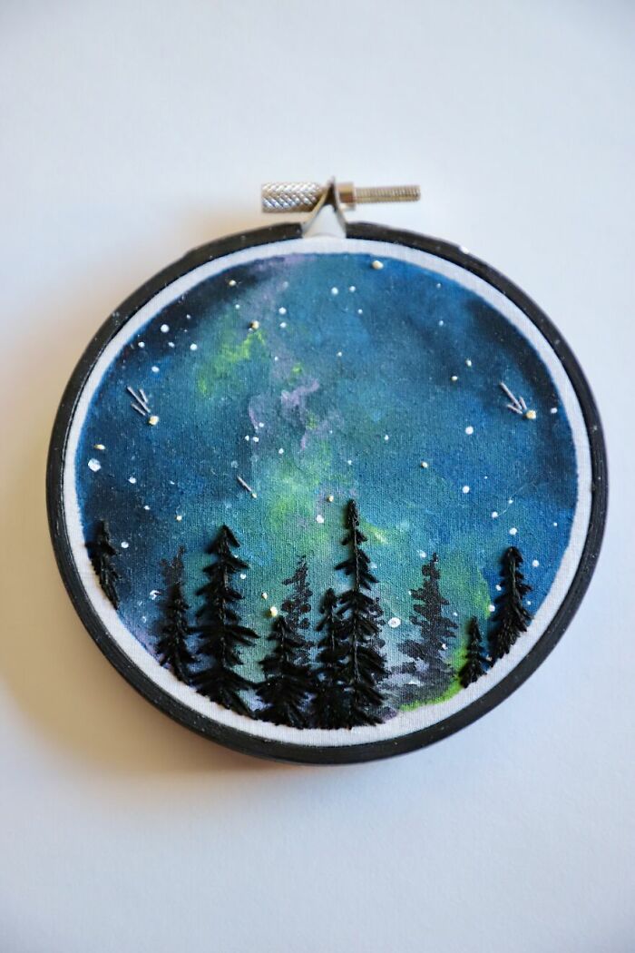 Embroidery work featuring a night sky with stars and silhouetted trees in a circular frame.