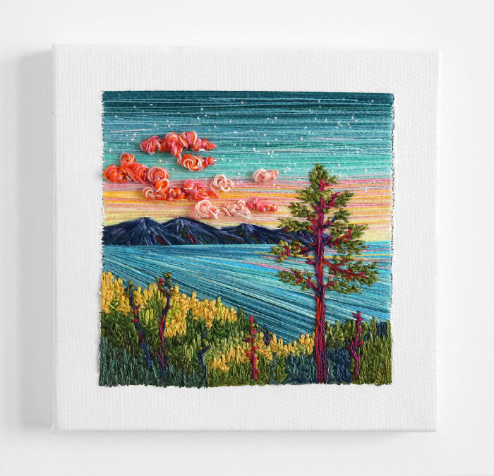 Vibrant embroidery landscape depicting a sunset over mountains and sea, featuring colorful clouds and a tree in the foreground.