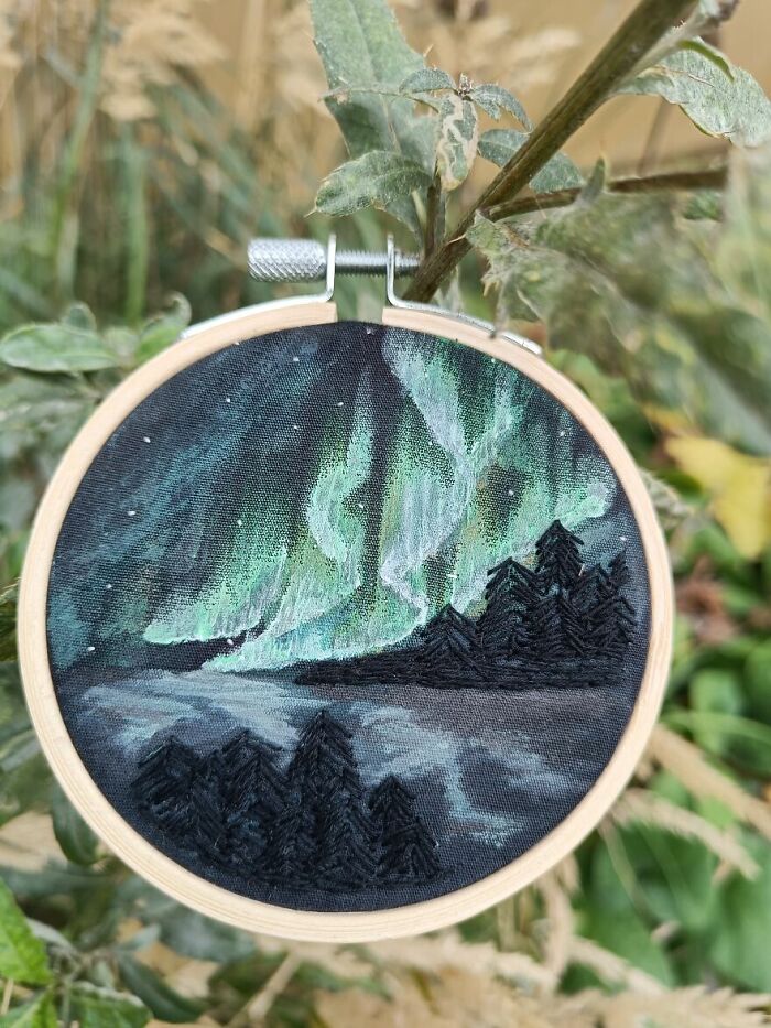 Embroidery hoop depicting a night scene with northern lights and trees, showcased by Bored Panda community.