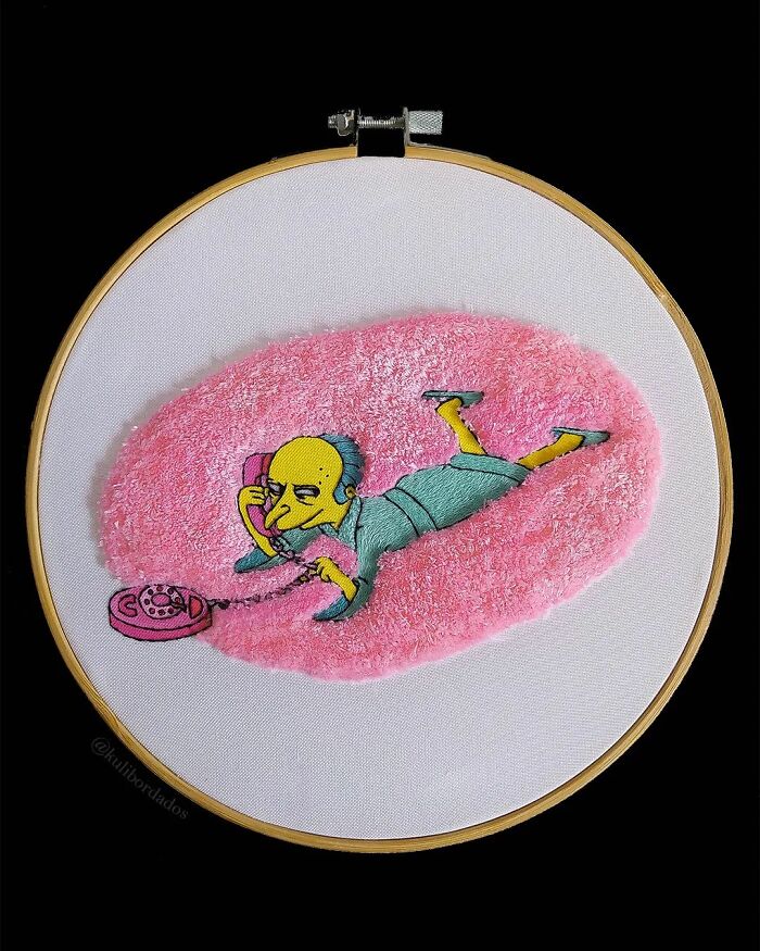 Colorful embroidery art of a character on a pink rug talking on a vintage phone.