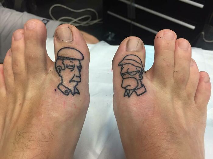 Simpsons tattoos on toes featuring two male characters with stern expressions.