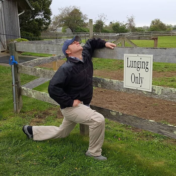 Man humorously posing by a "Lunging Only" sign, ensuring life is never boring for his partner.