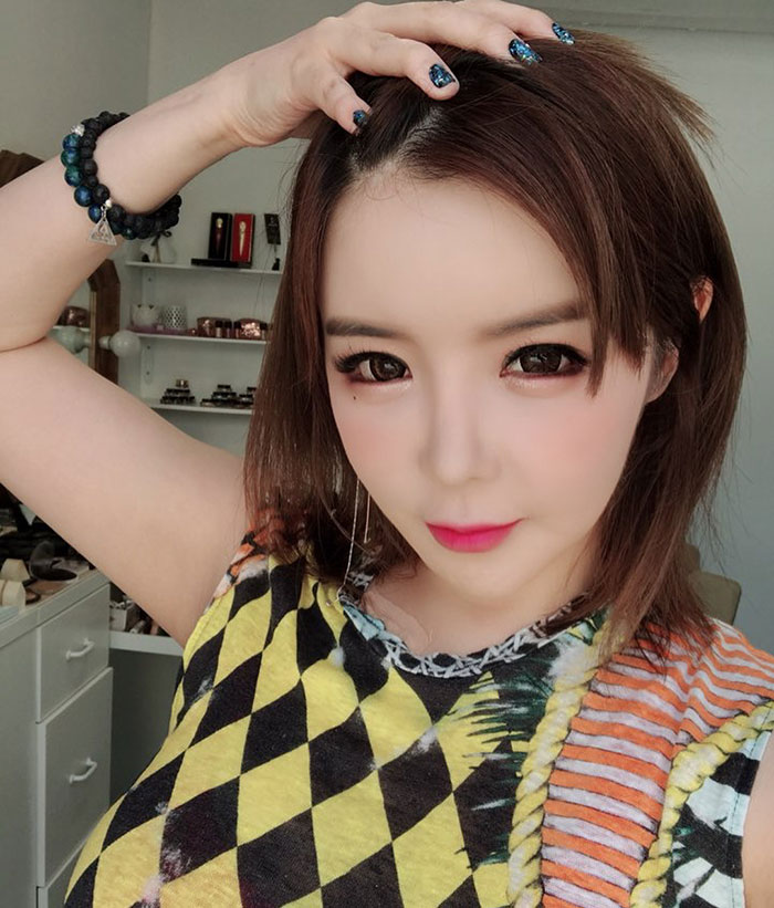 K-Pop star posing indoors with hand on head, amid plastic surgery rumors.