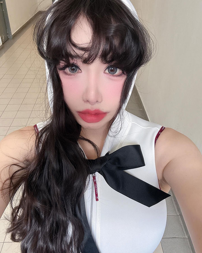 K-Pop star poses in a sleeveless outfit with long dark hair, amid plastic surgery rumors.